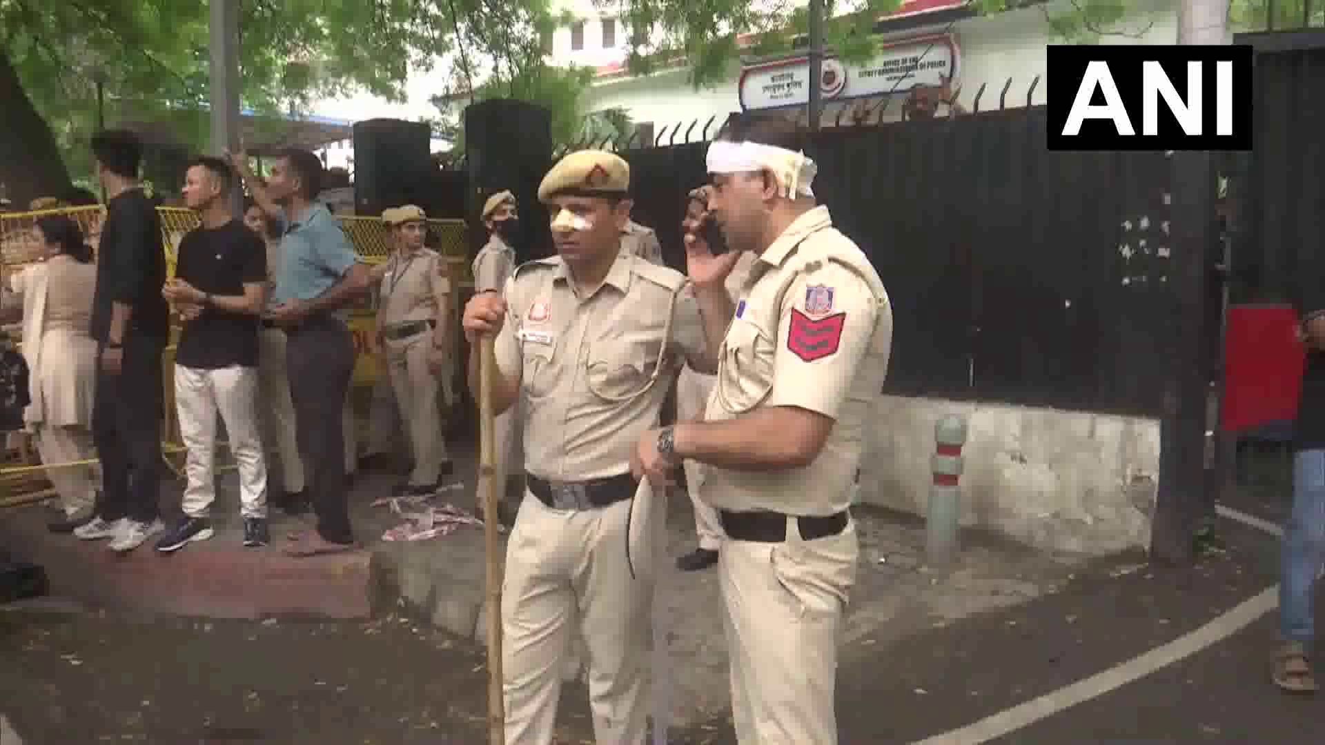 A policeman with a bandaged head takes a phone call outside the DCP office