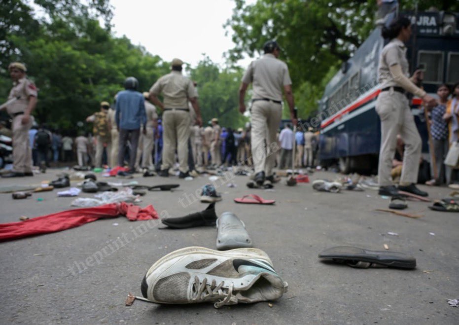 Shoes, slippers and clothes scattered across an empty road as police walk away