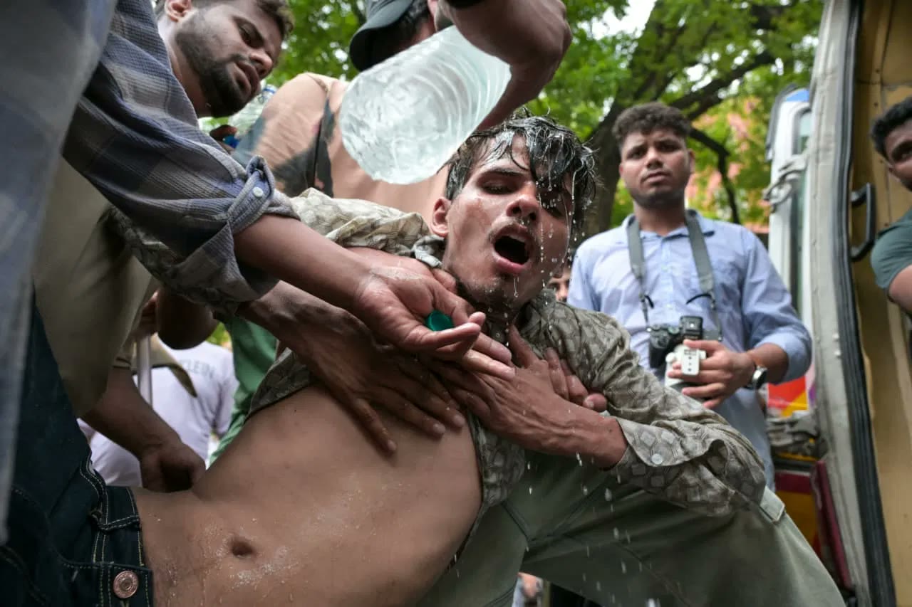 A drenched, dazed young man is held up by people around him