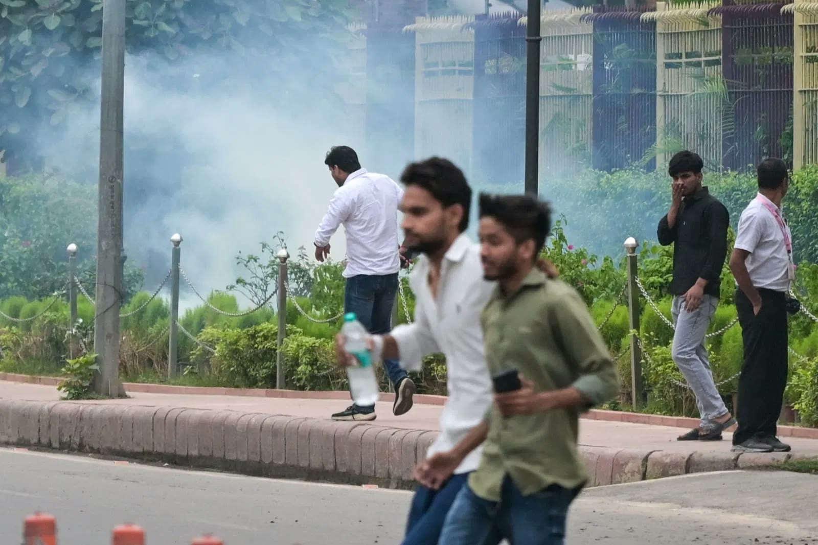 Protesters run through tear-gas smoke under the trees